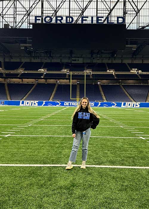 UF Online sport management and tourism, hospitality and event management student Kalena Miles stands on the football field of the Detroit Lions.