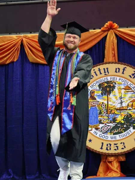UF Online student Ryan Longo walks across the stage at graduation
