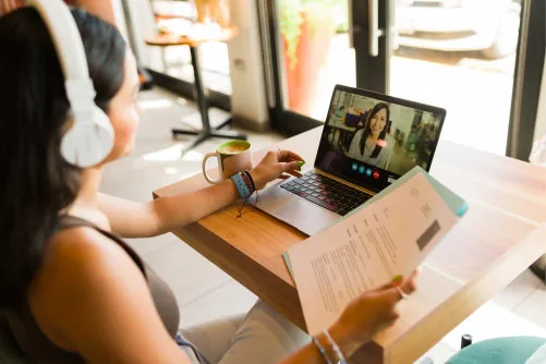 Student wearing headphones while seated at desk working at laptop.