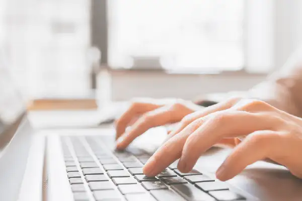 Hands typing on laptop keyboard.